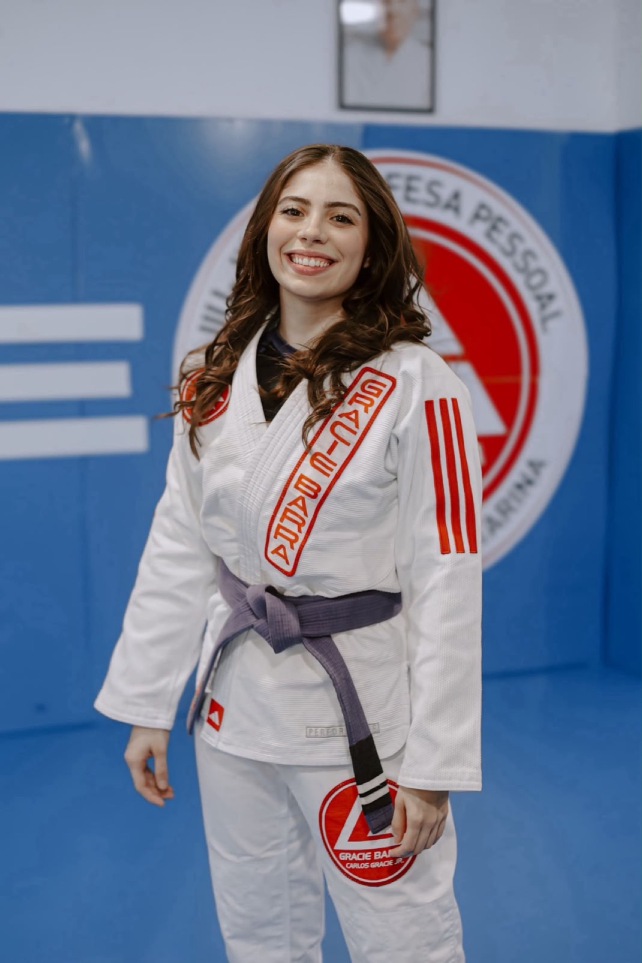 Instrutora Julia, faixa roxa, sorrindo no tatame da GB Tubarão